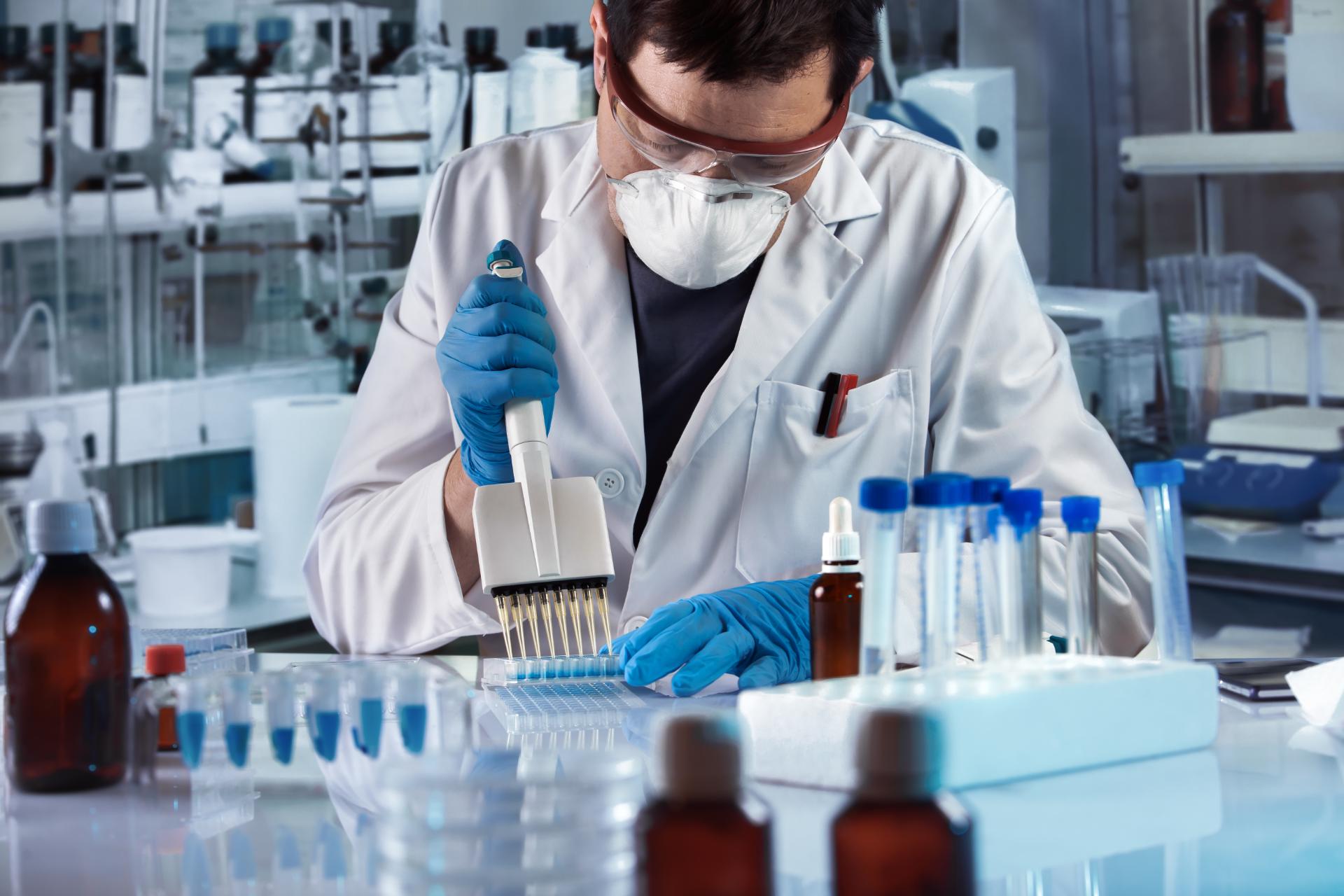 Técnico con mascarilla en un laboratorio rellenando viales